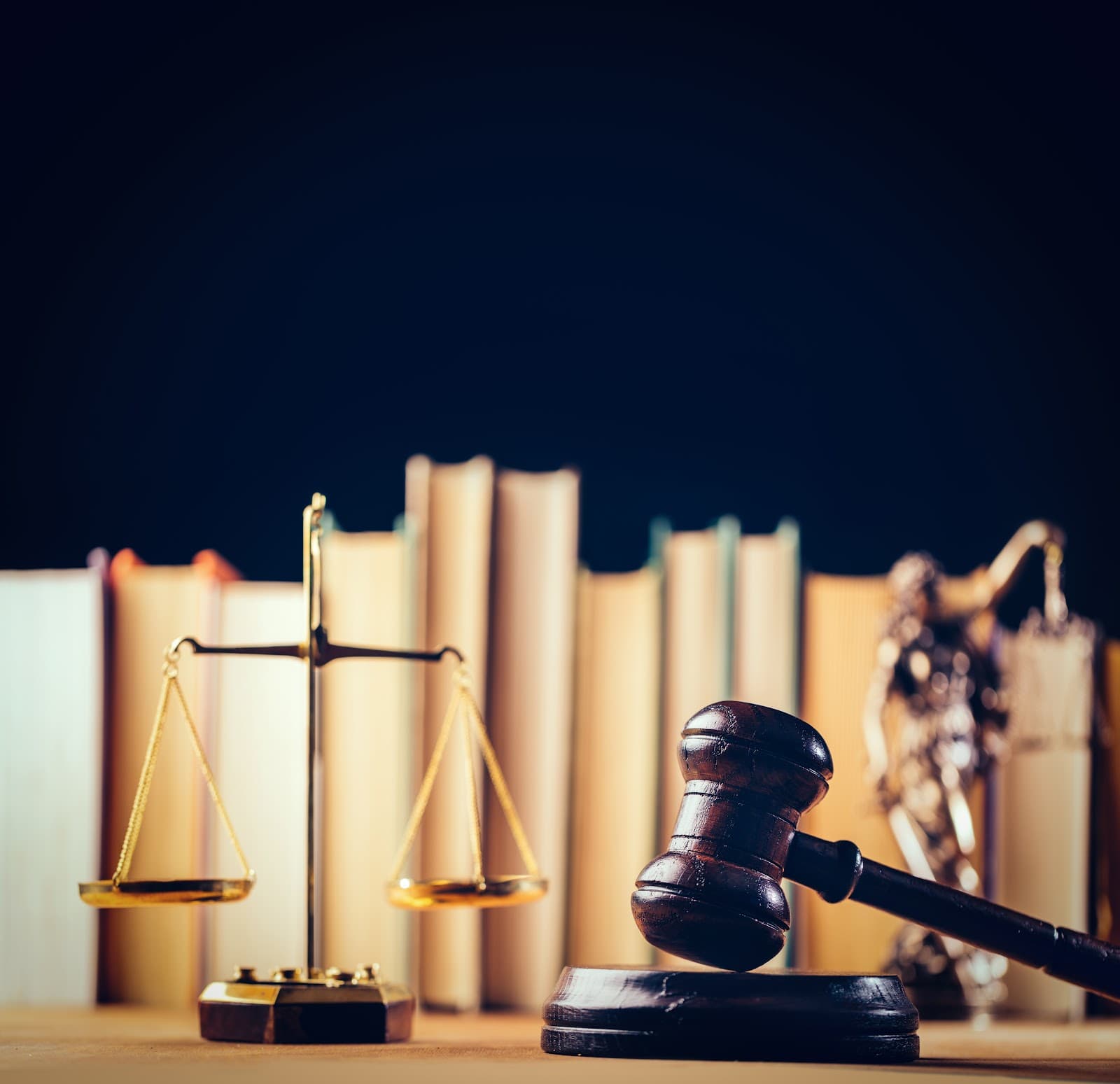 Balança da justiça, martelo e livros de leis sobre uma mesa de madeira.