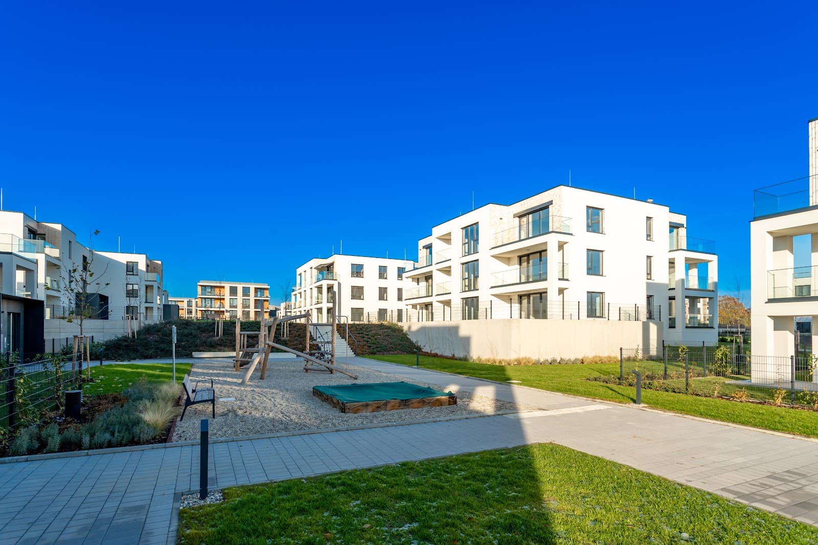 Complexo residencial moderno com area de lazer e playground em dia ensolarado.