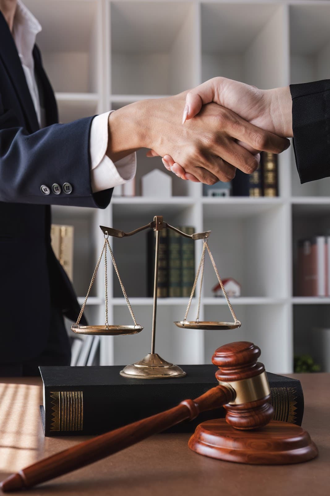 Aperto de mao com balanca da justica e martelo sobre a mesa