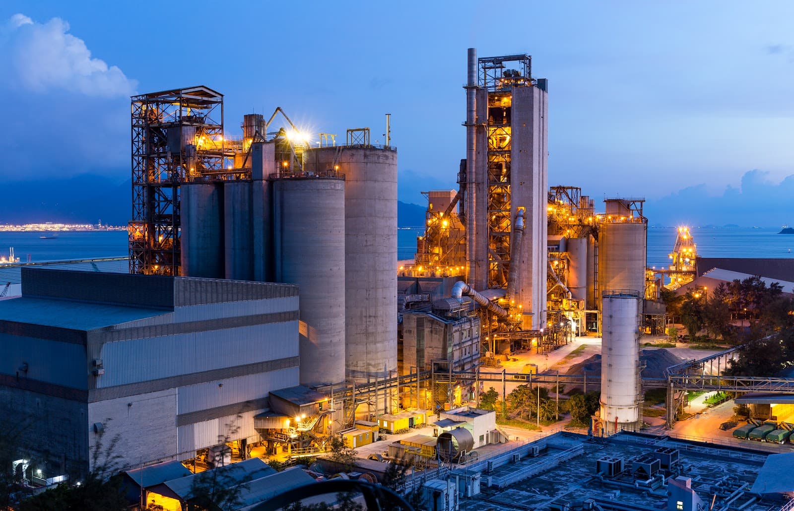 Planta industrial de cimento com silos e estruturas metalicas sob ceu claro