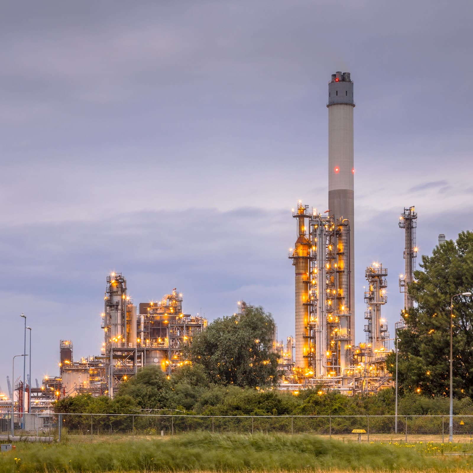 Refinaria de petróleo moderna com torres industriais sob o céu claro.