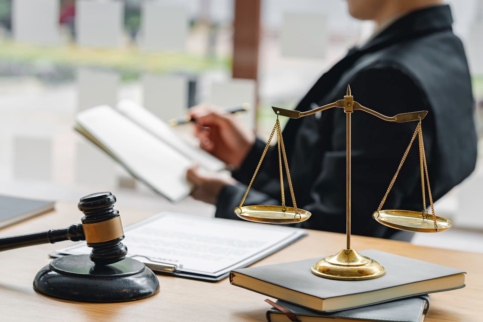 Balança da justiça e malhete sobre mesa de madeira em escritório jurídico