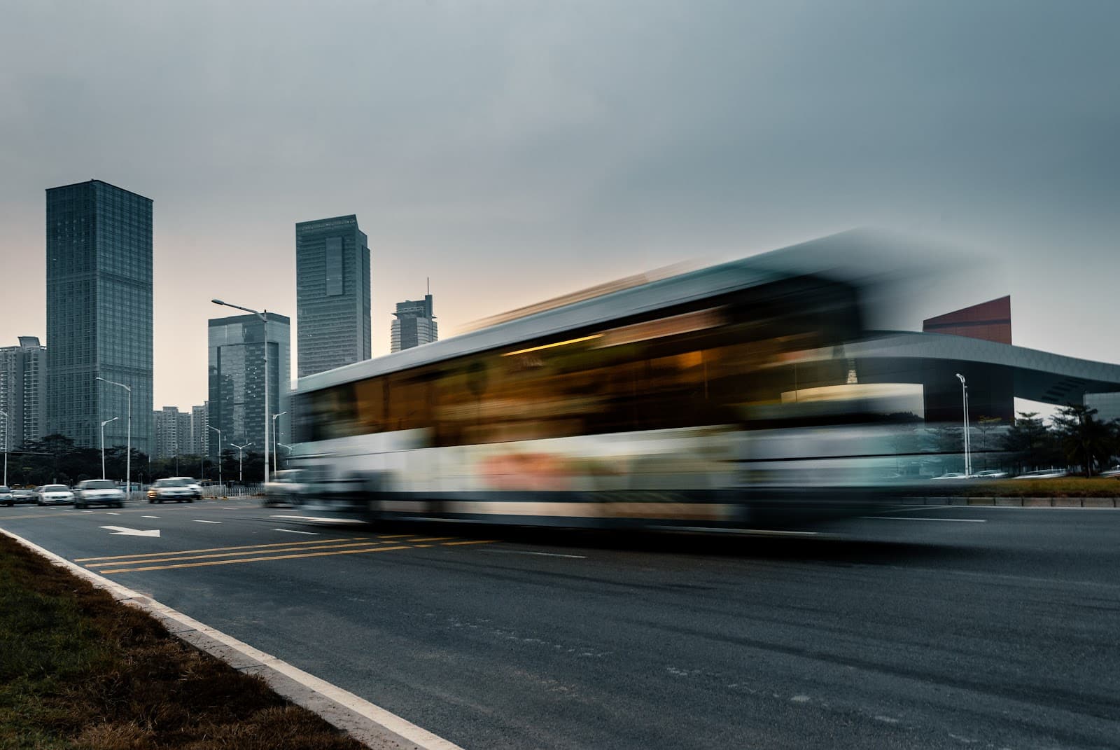 Onibus em movimento em avenida urbana com efeito de desfoque.
