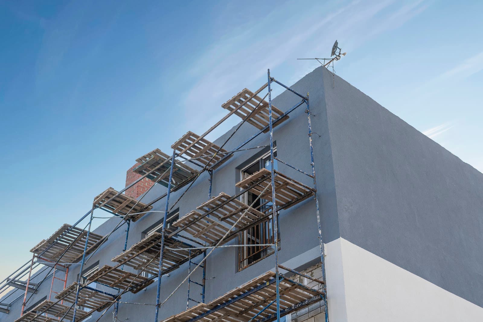 Canteiro de obras com andaimes e estrutura de edificio em construcao.