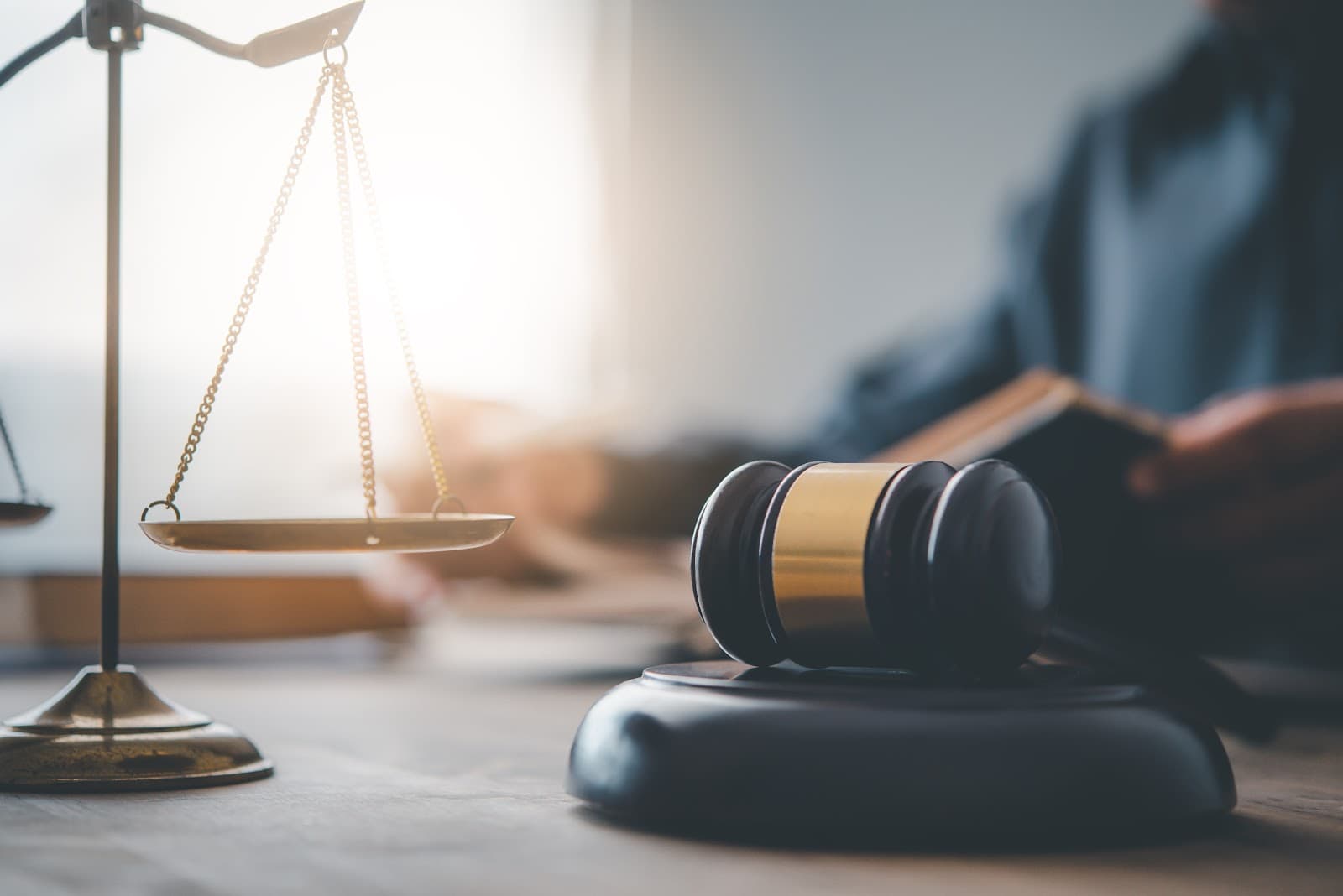 Martelo de juiz e balanca da Justica sobre superficie de madeira.