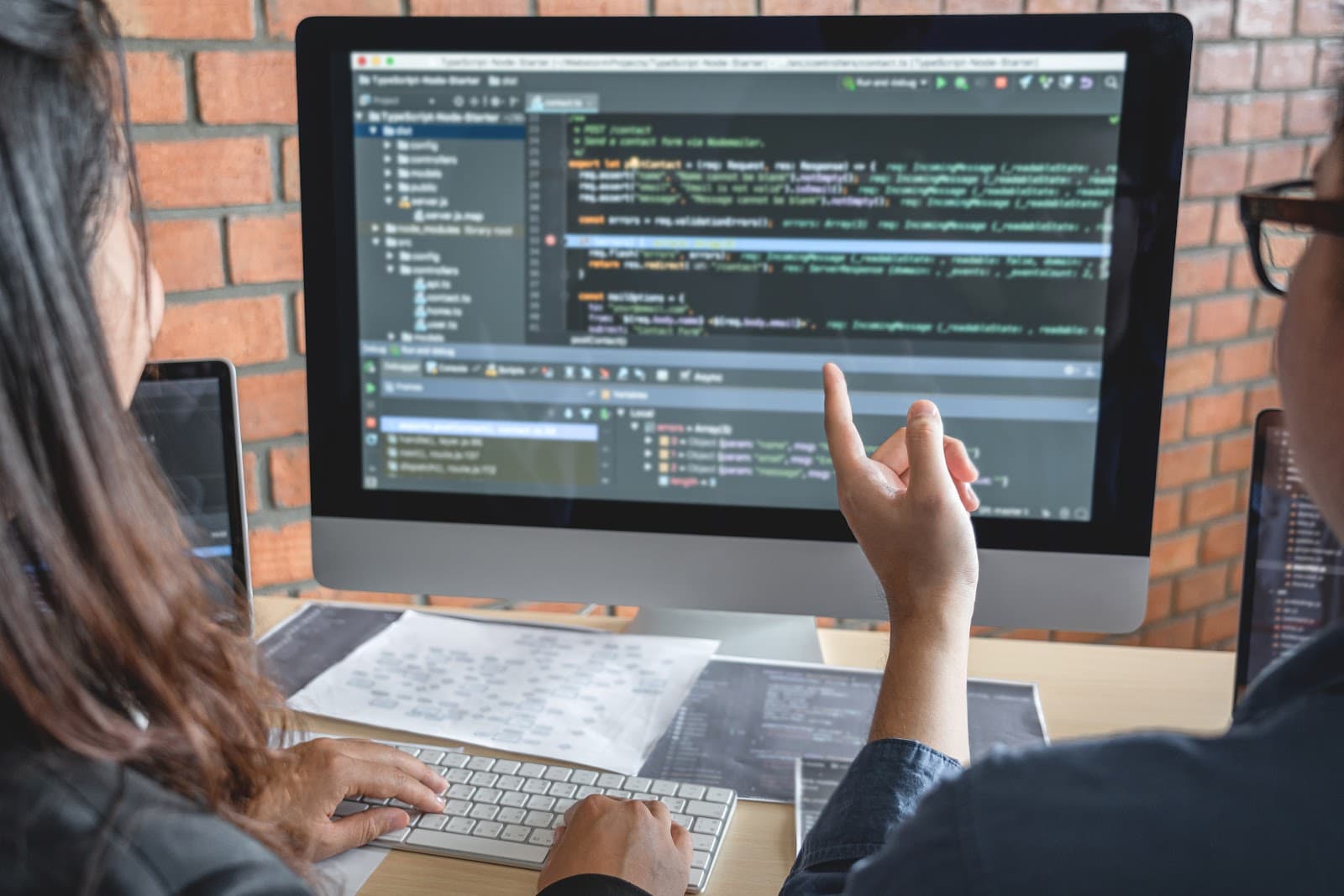 Profissionais analisando códigos em telas de computadores no ambiente de trabalho