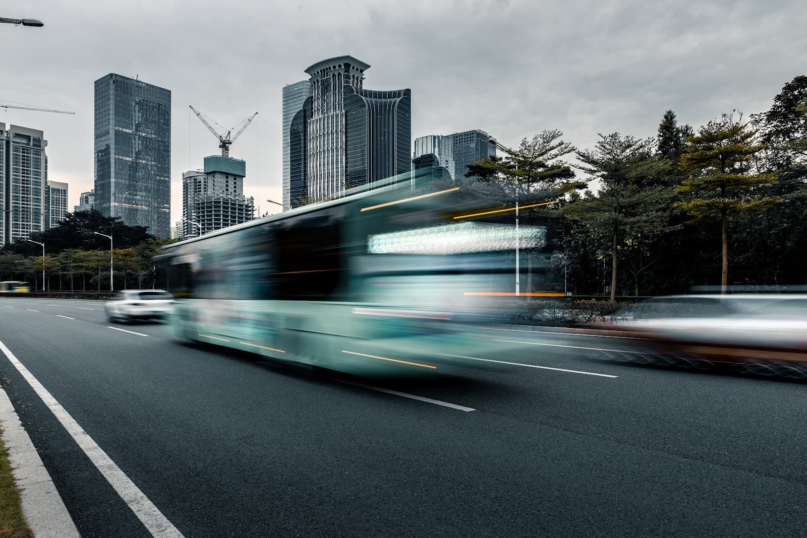 Onibus em movimento em rua urbana com predios ao fundo.