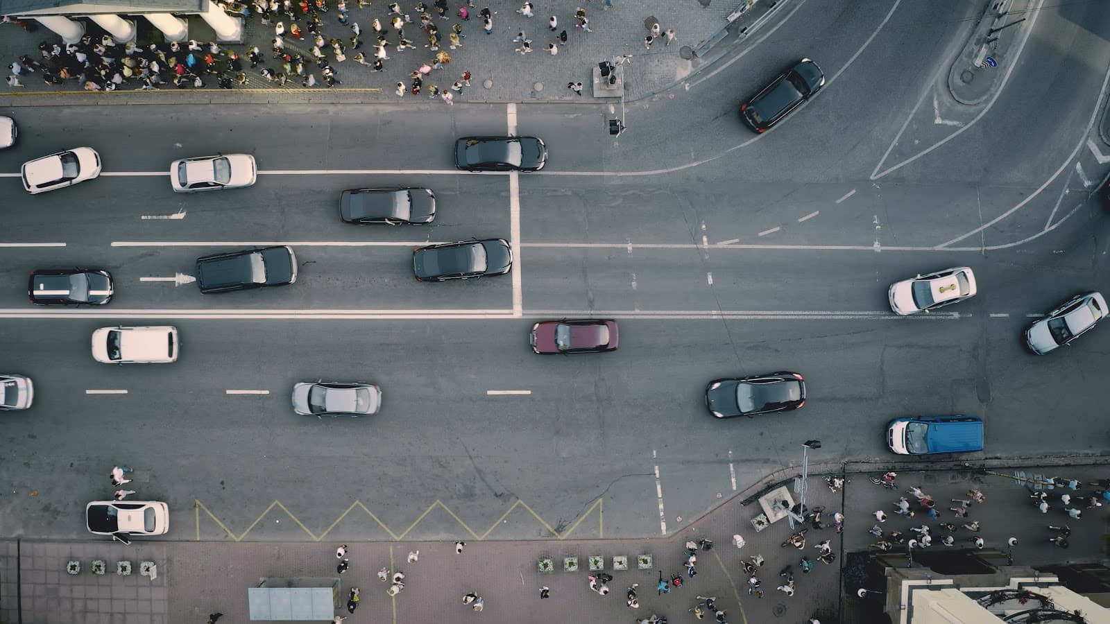 Vista aerea de carros e pedestres circulando em ruas urbanas movimentadas.