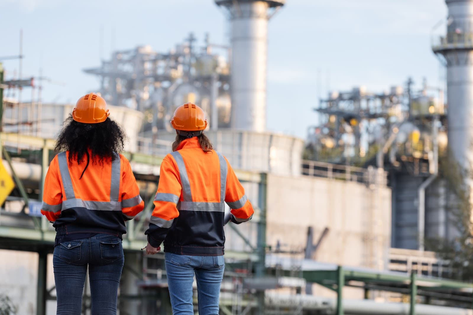 Duas engenheiras em pé em uma planta industrial com equipamentos ao fundo