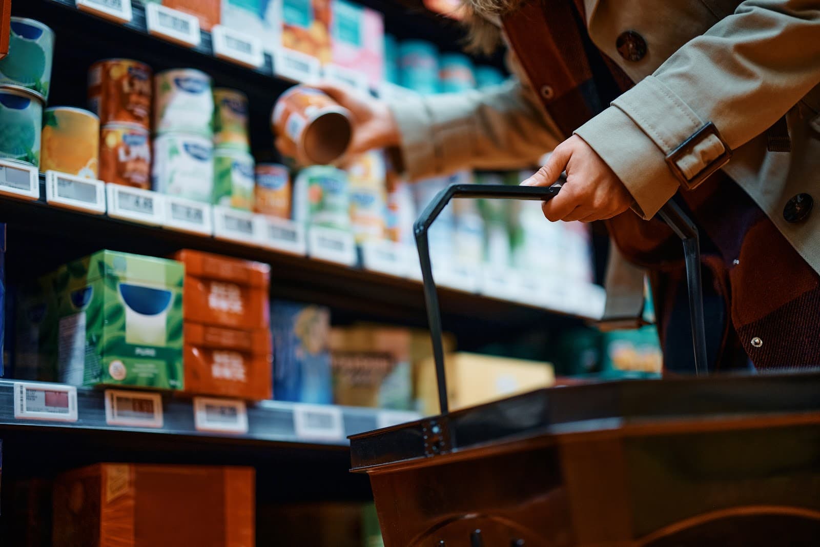 Pessoa adulta fazendo compras de supermercado em corredor com prateleiras cheias