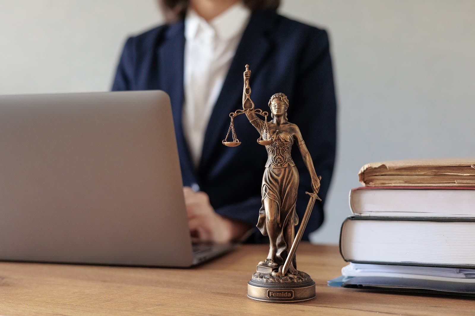 Estatueta da deusa da justiça em mesa de madeira com fundo desfocado
