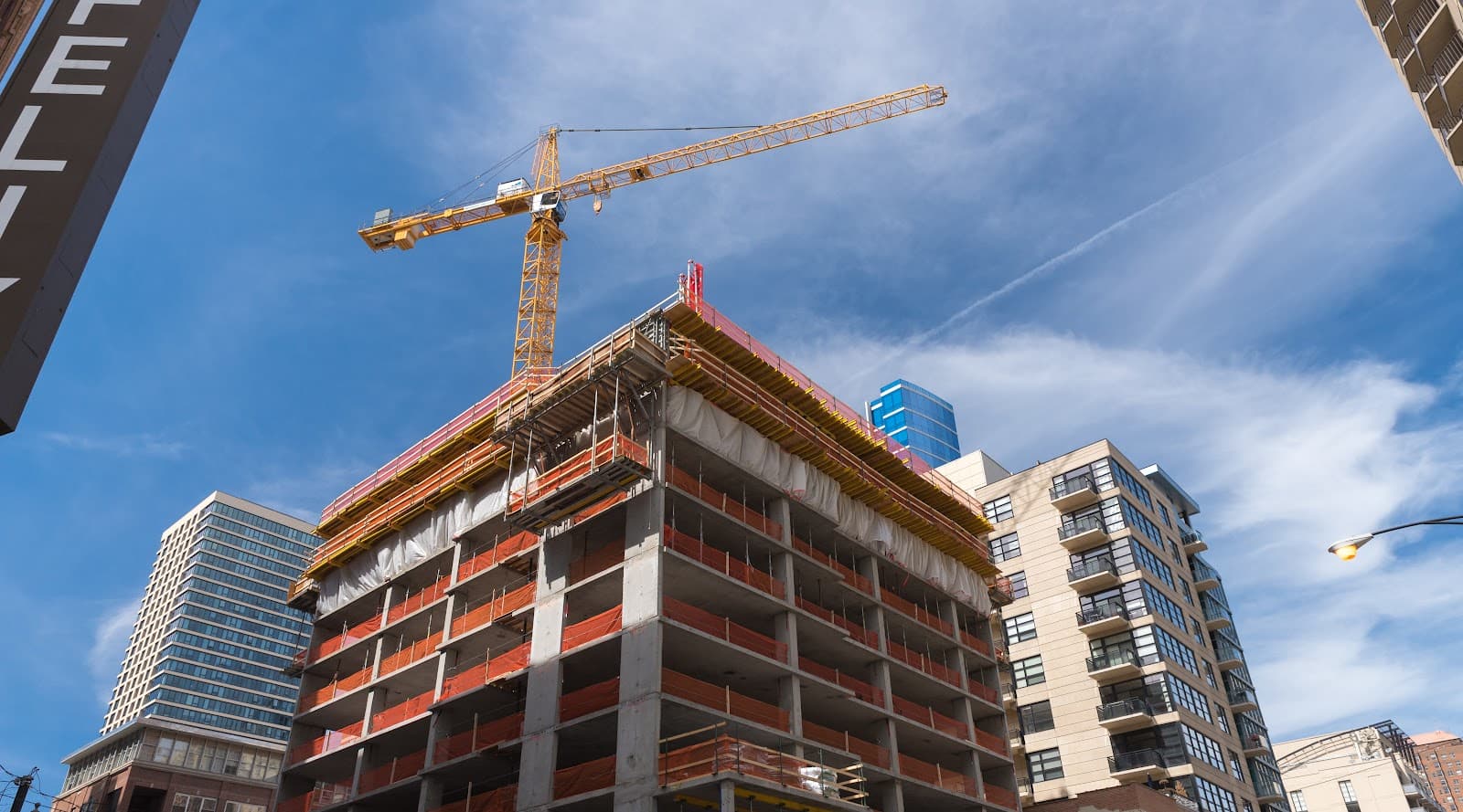 Edificio em construcao com grande guindaste amarelo sob ceu limpo.