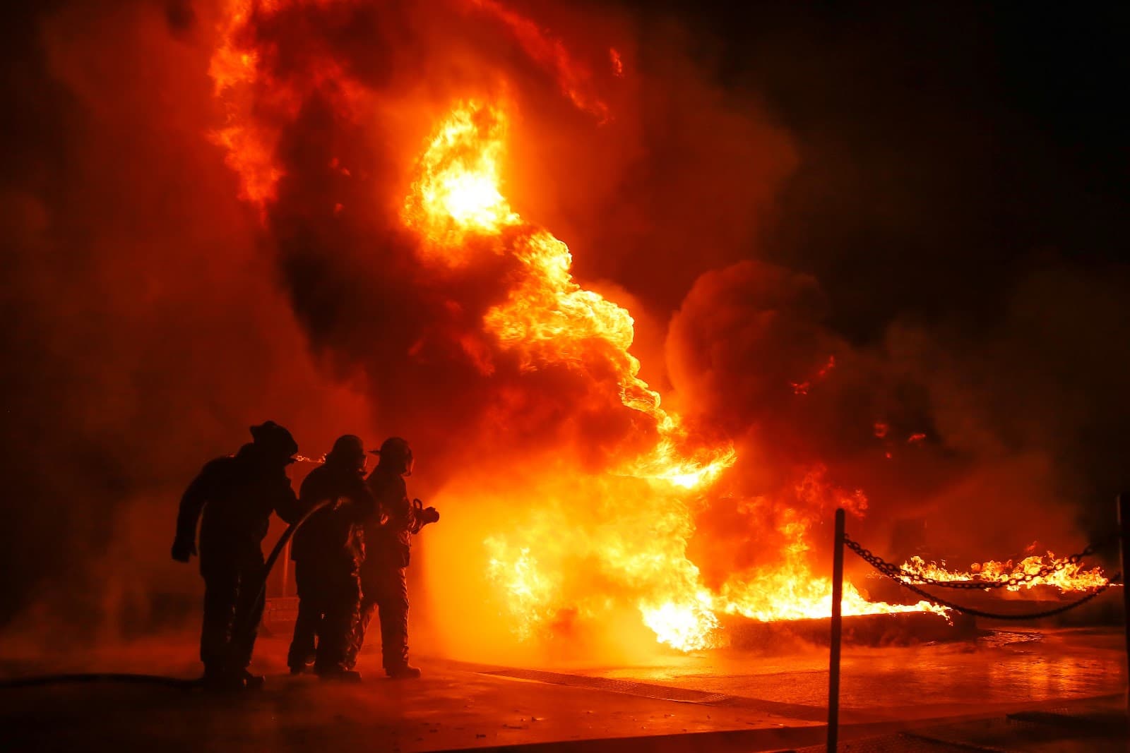 Bombeiros combatendo um grande incendio a noite em area urbana.