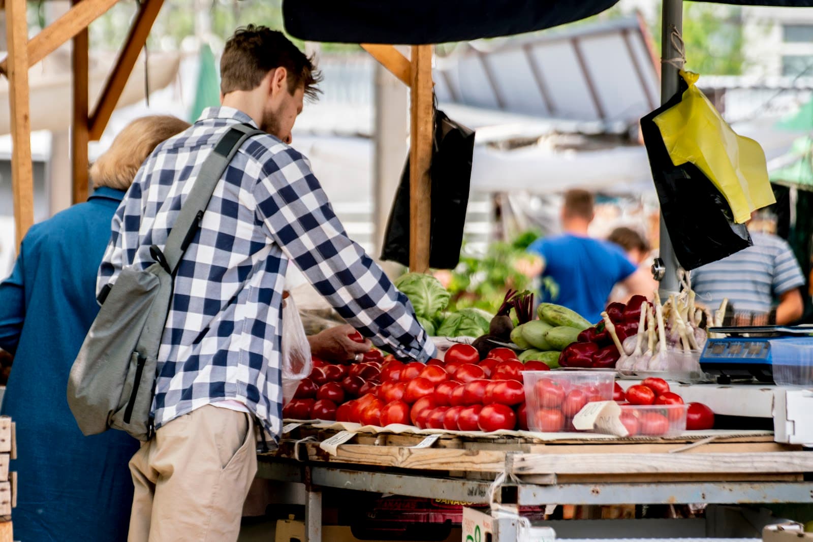 Homem faz compras em feira ao ar livre com frutas e verduras