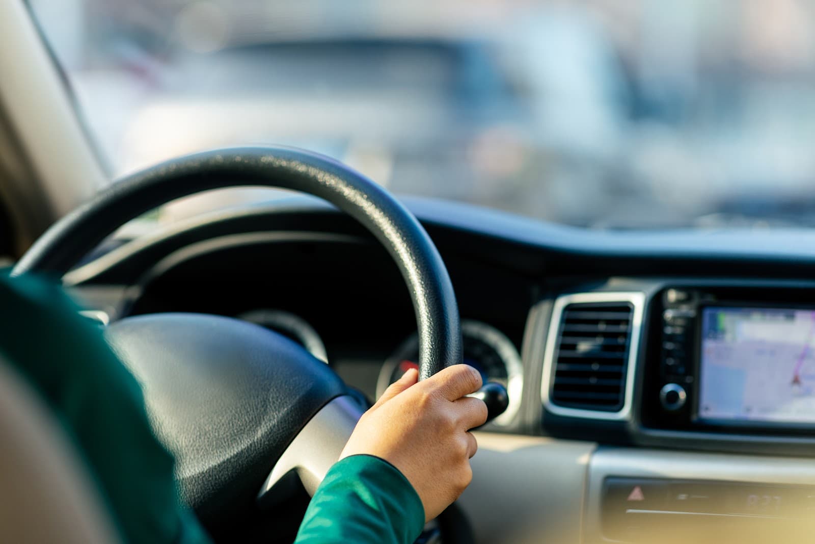 Pessoa dirigindo um carro segurando o volante em primeiro plano