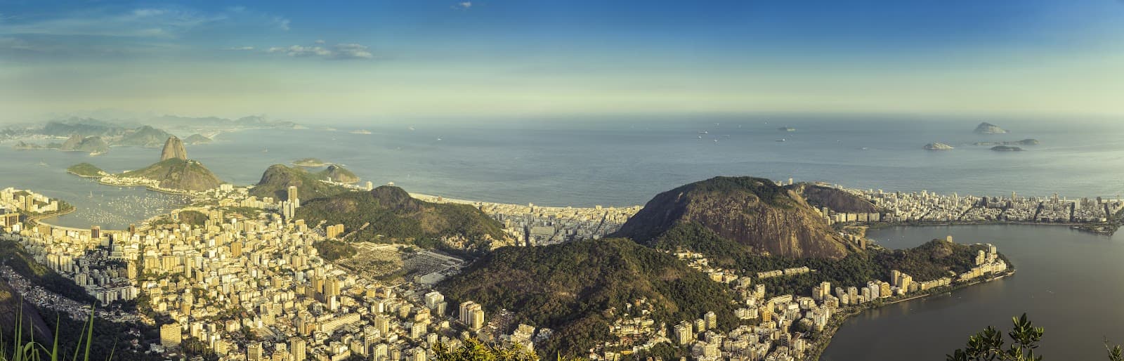 Panorama de praia urbana com faixa de areia e edifícios ao fundo.