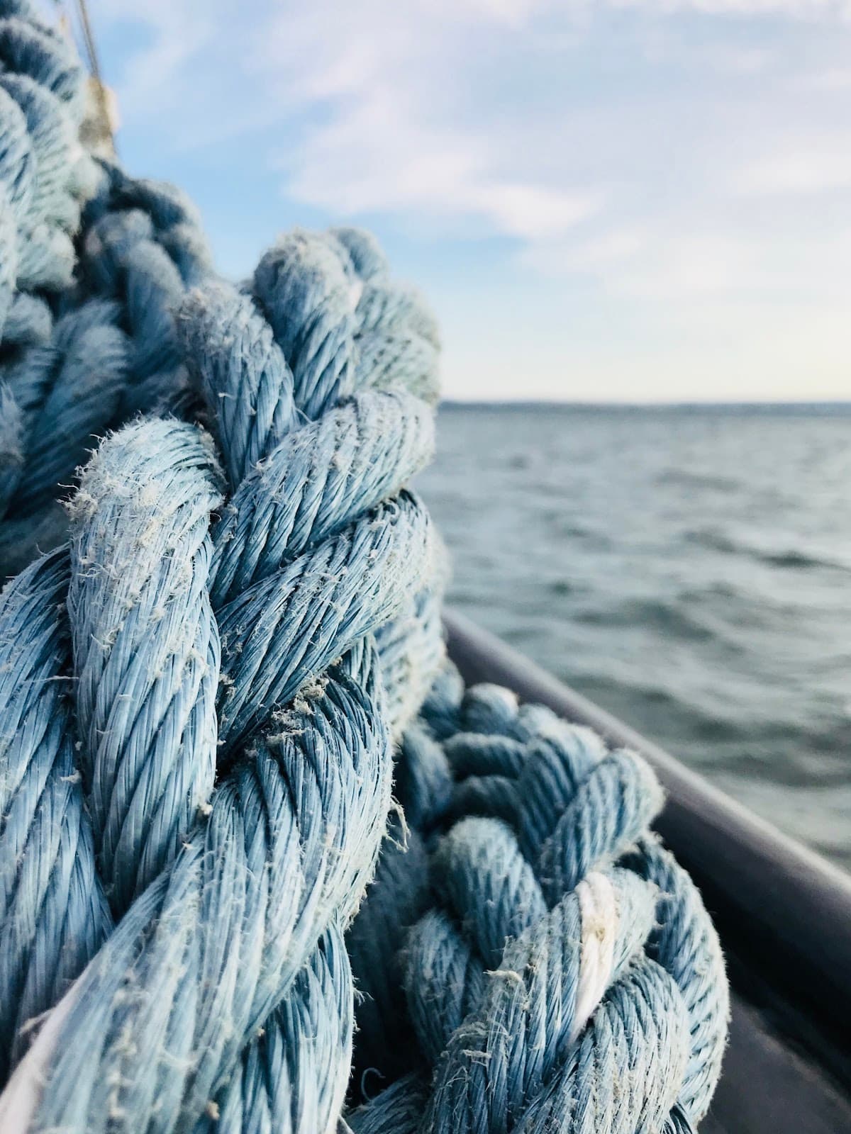 Corda azul em primeiro plano, com água e céu ao fundo.