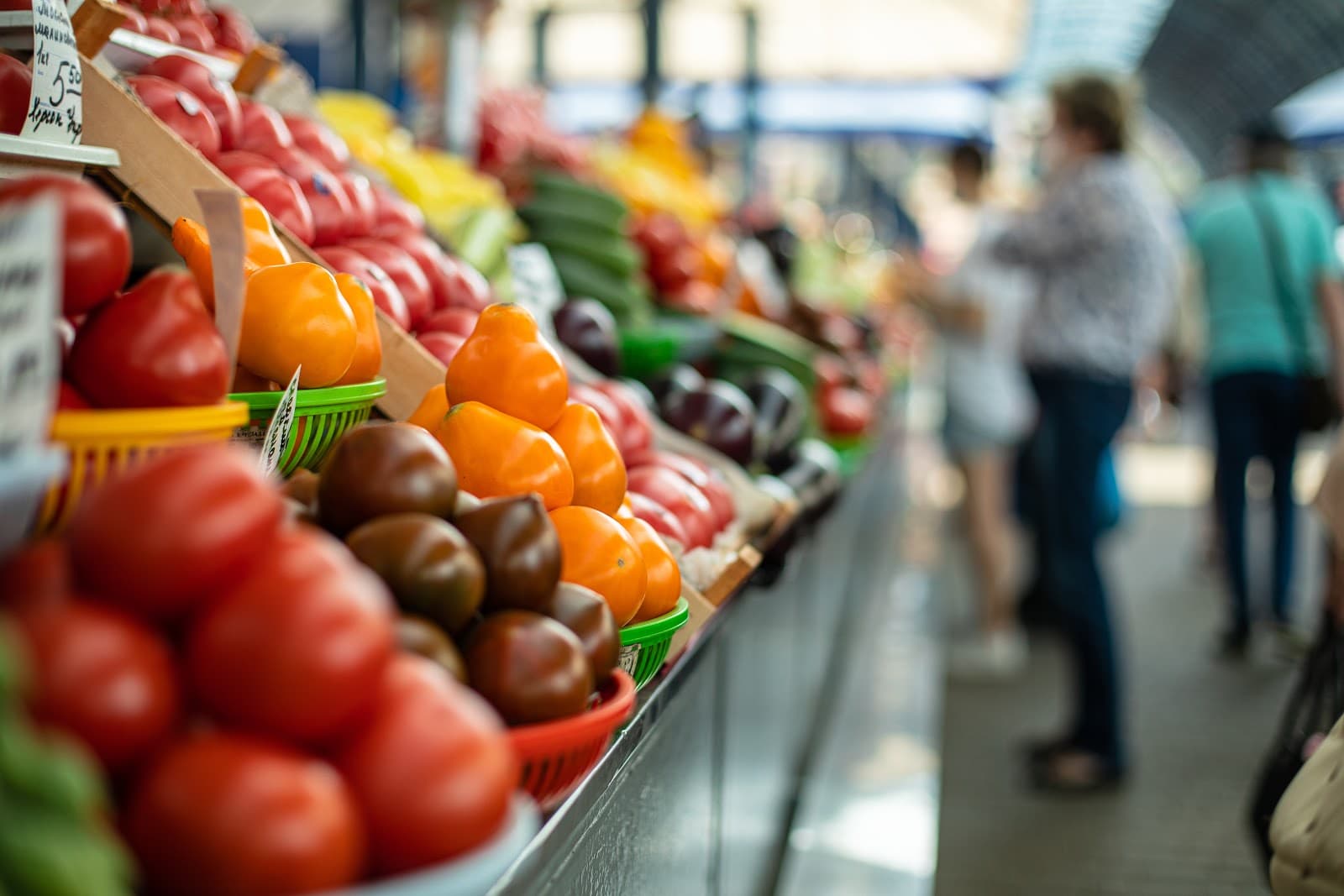 Banca de mercado colorida com frutas e legumes frescos expostos para venda.