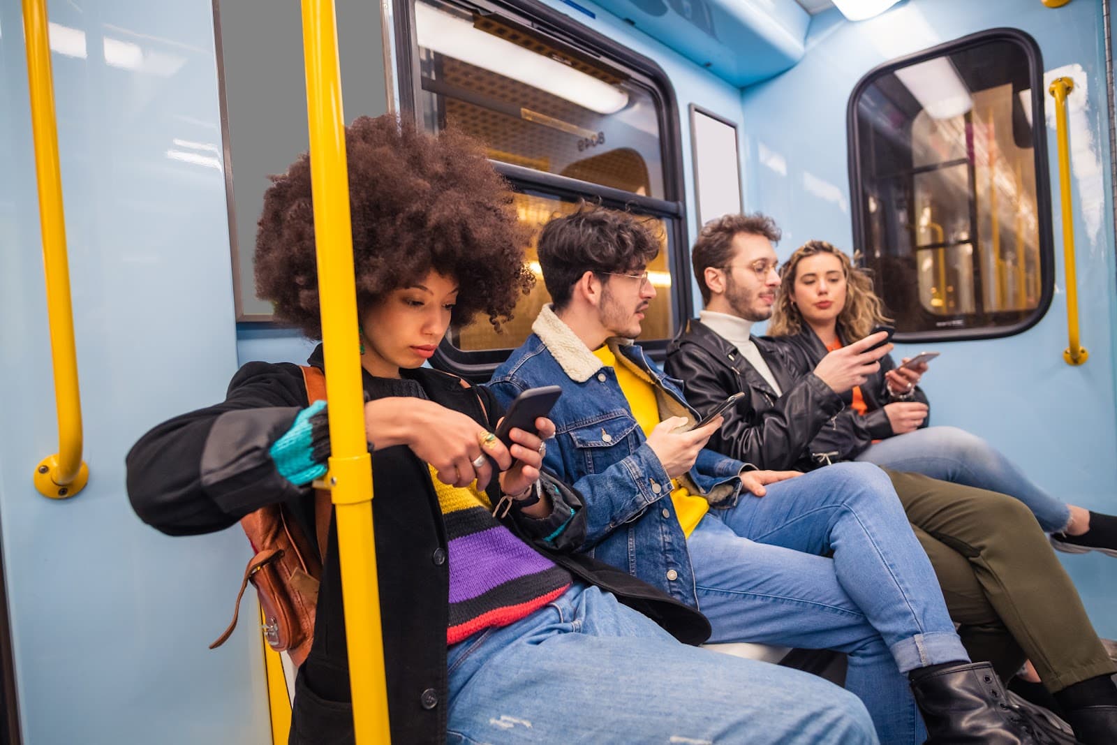 Jovens utilizam smartphones em transporte publico.