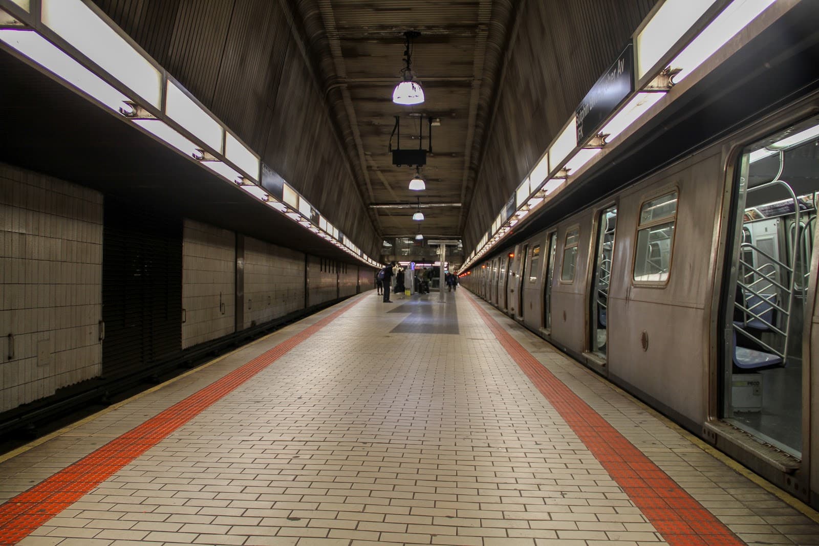 Estação de metrô subterrânea com trem parado na plataforma.