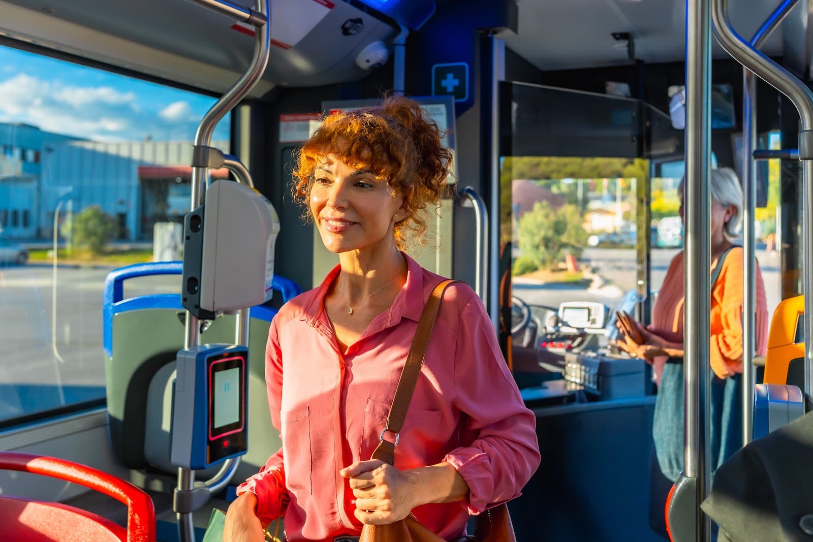 Mulher sorridente viaja sentada em um ônibus durante o dia.