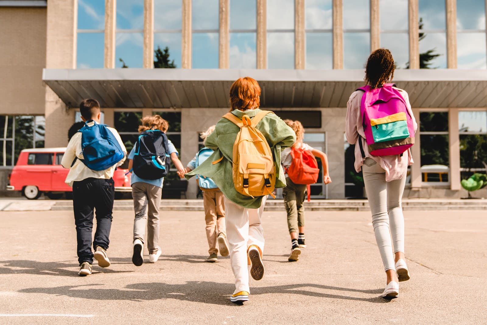 Crianças correndo e brincando em área escolar ao ar livre.