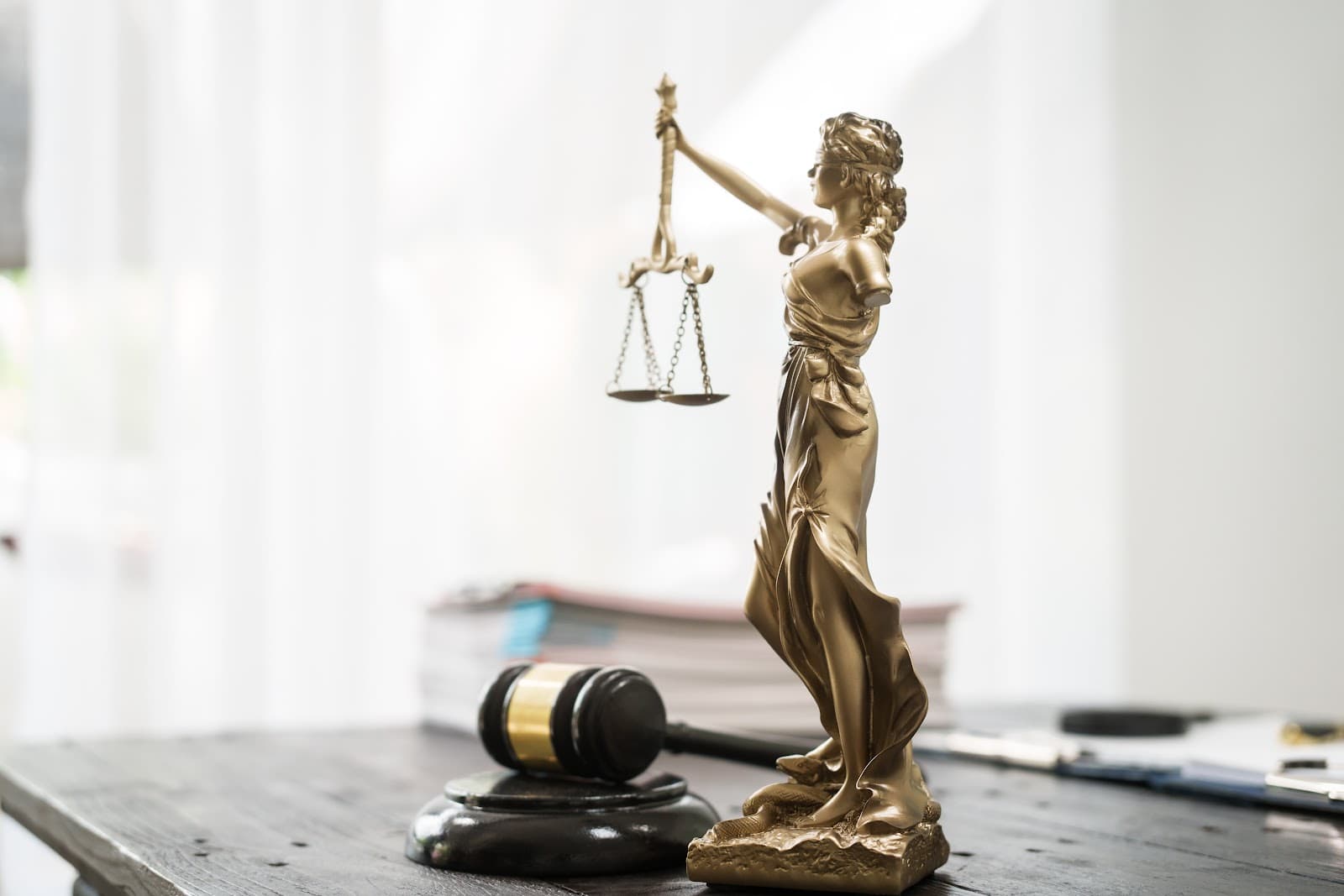 Estatueta da deusa da justiça com balança sobre mesa de madeira