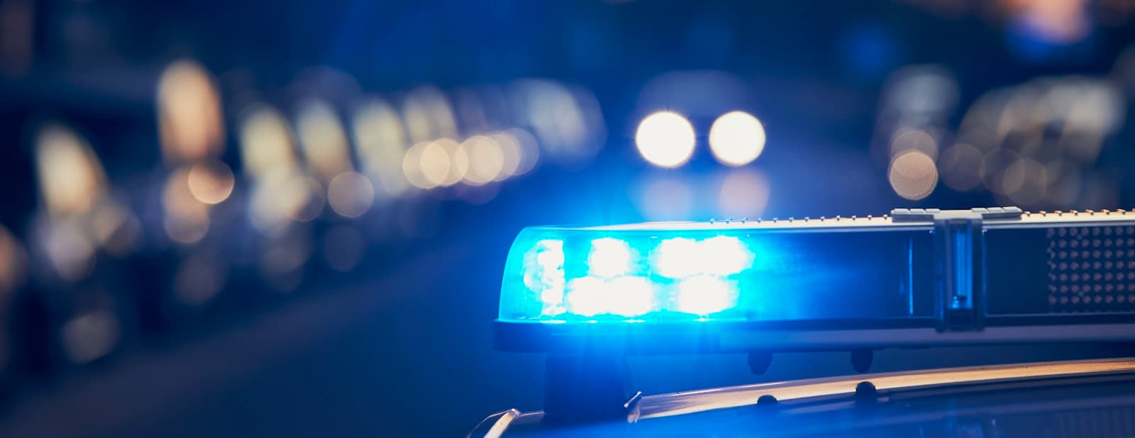 Giroflex de viatura policial iluminado durante a noite em ambiente urbano.