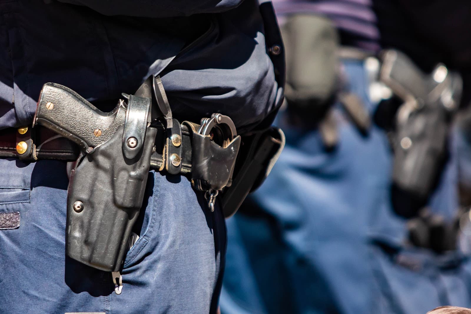 Cinto de policial uniformizado com coldre e algemas.
