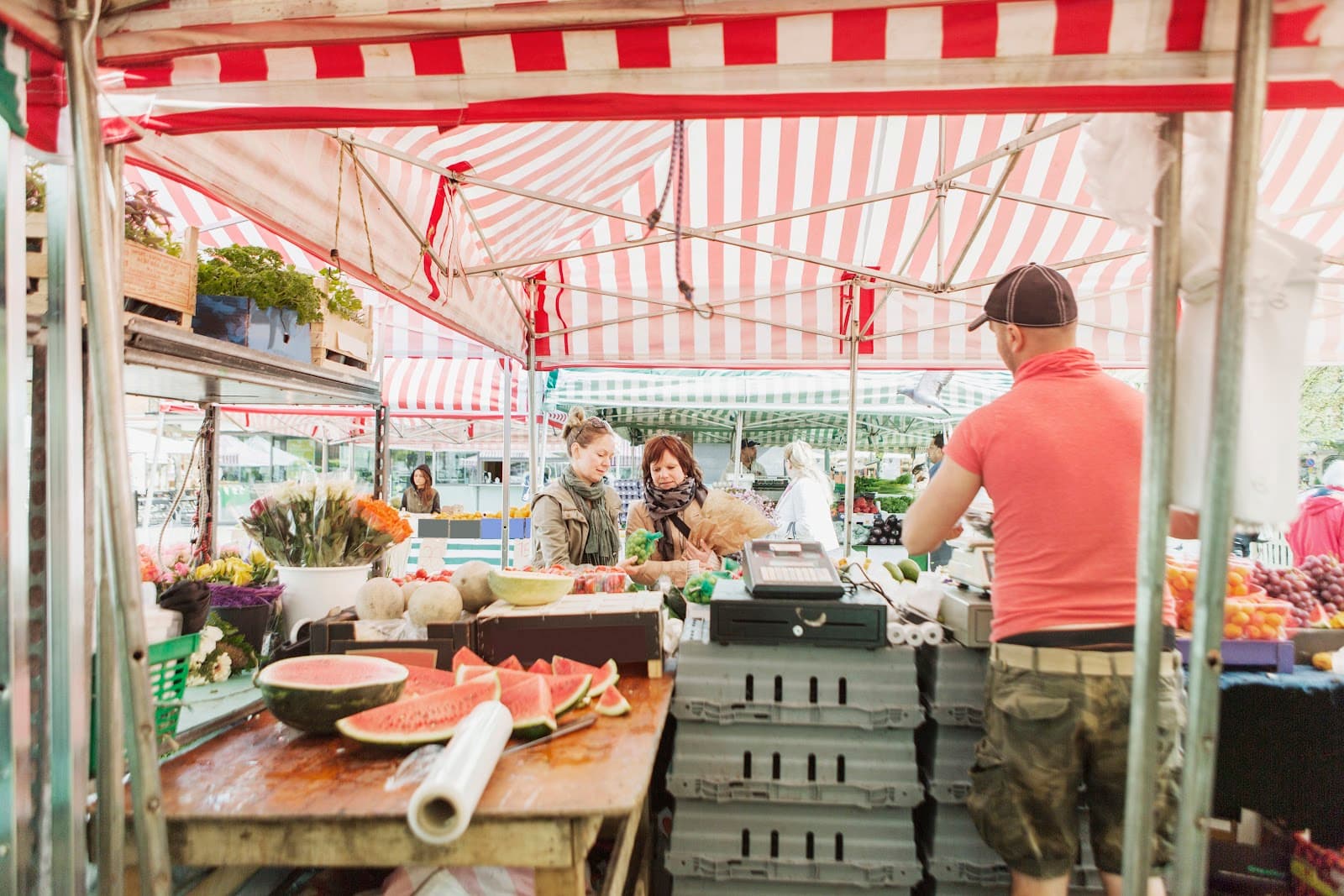 Pessoas comprando frutas e legumes em feira livre.
